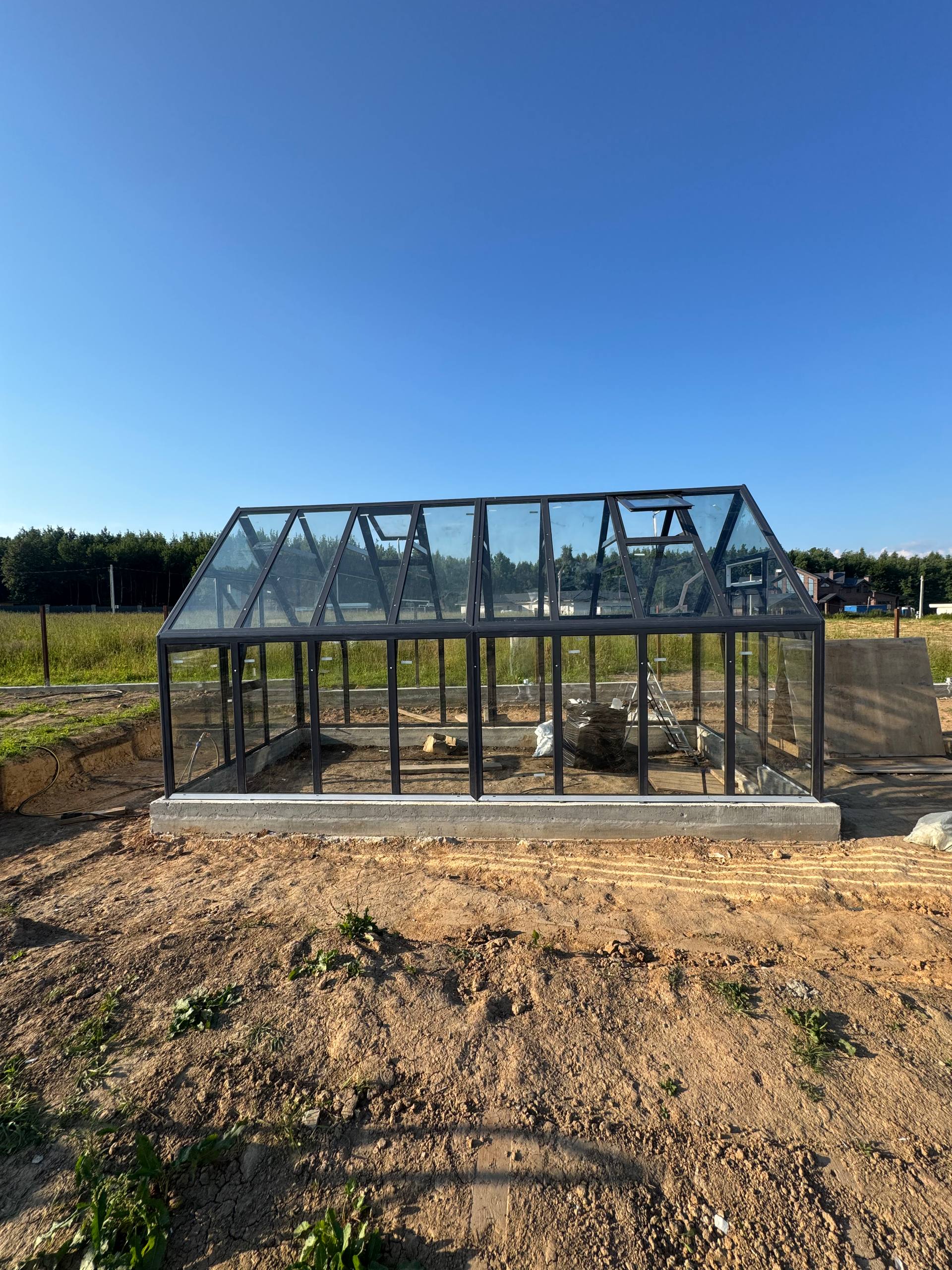 Процесс монтажа стеклянной теплицы S-Glass на частном участке рядом с загородным домом